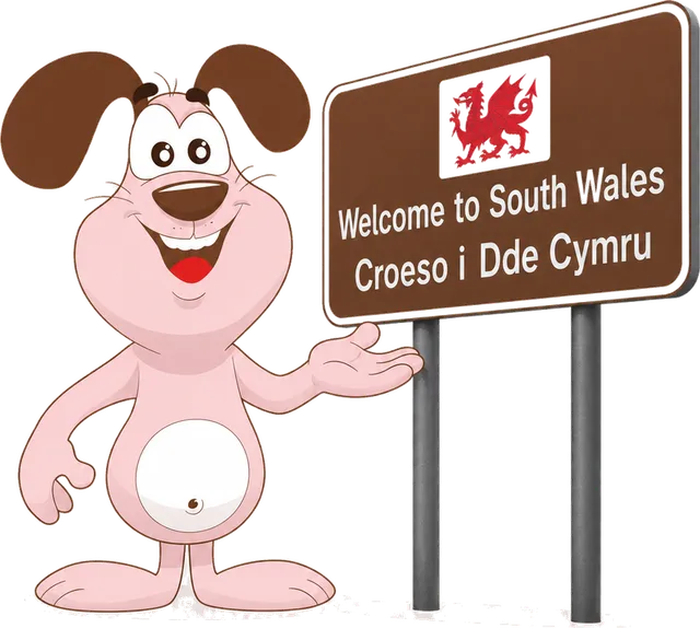Marley the MyWaggyTails mascot beside a Welcome to Wales sign